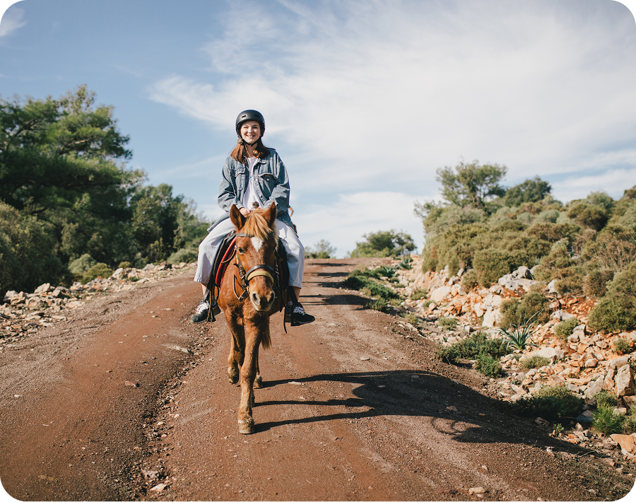 Person riding a horse on dirt path