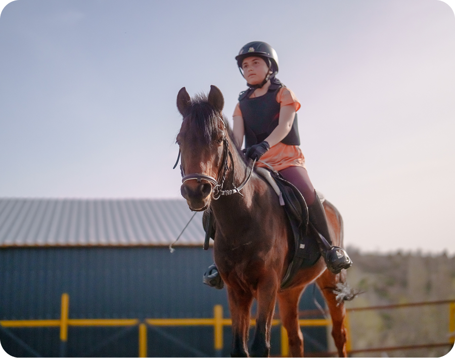 Young rider on brown horse outdoors