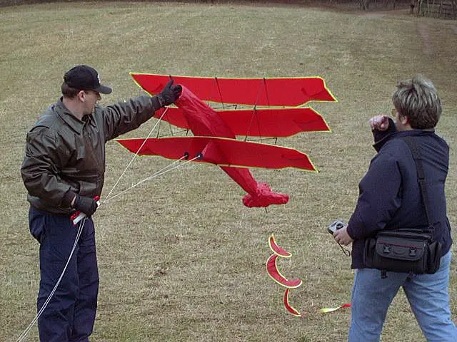 Two people handling a red kite