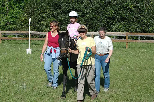 Group assisting child on horseback