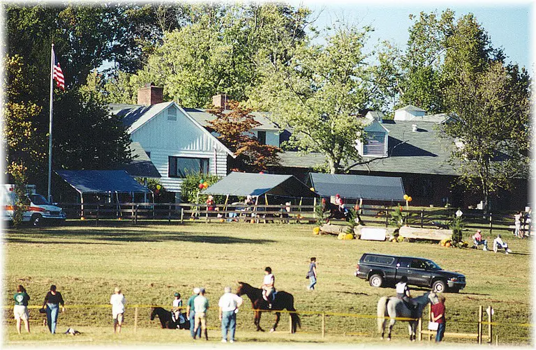 Horse riders near rural farmhouse