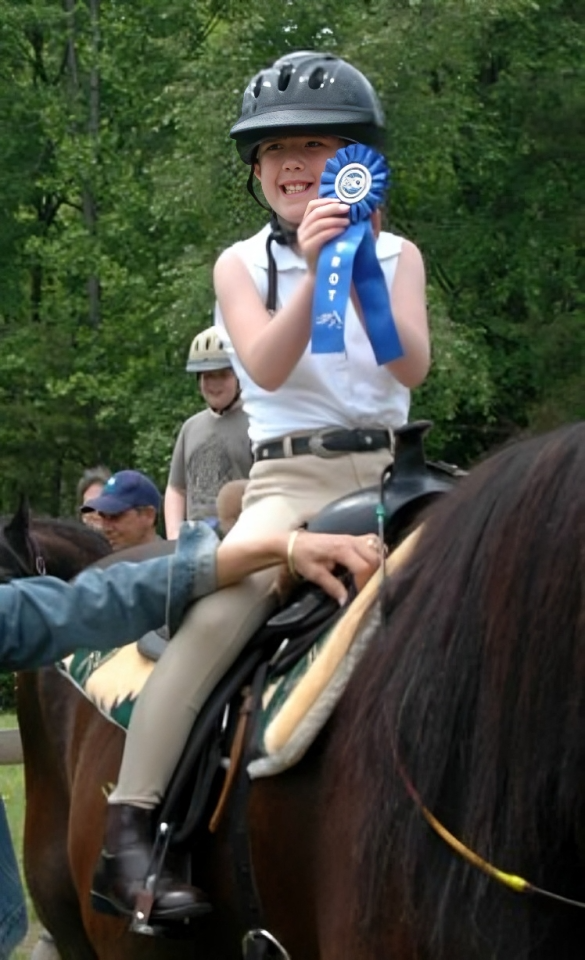 Young rider celebrating with blue ribbon