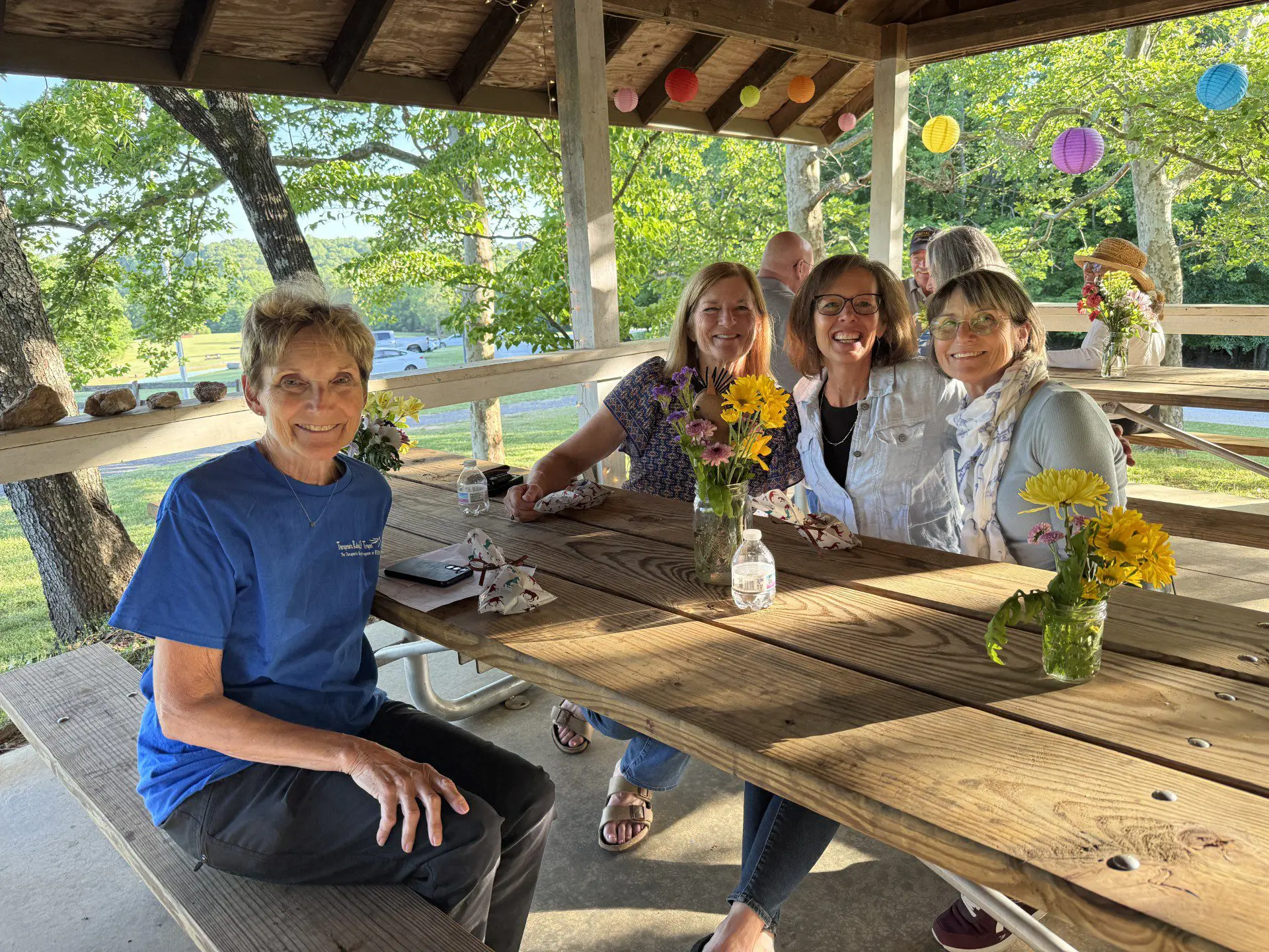 Women smiling at picnic table under pavilion
