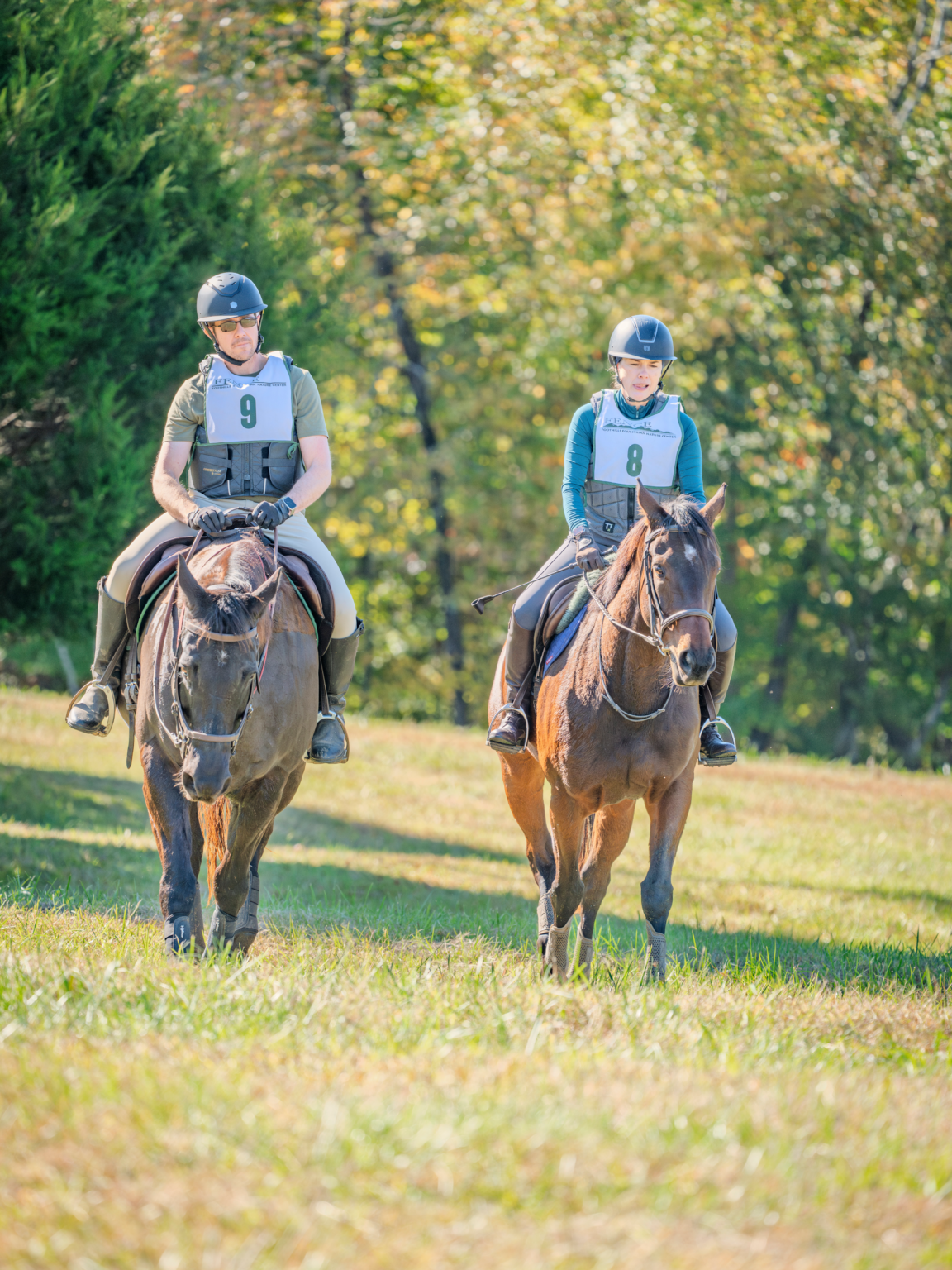 Two riders on horses in grassy field