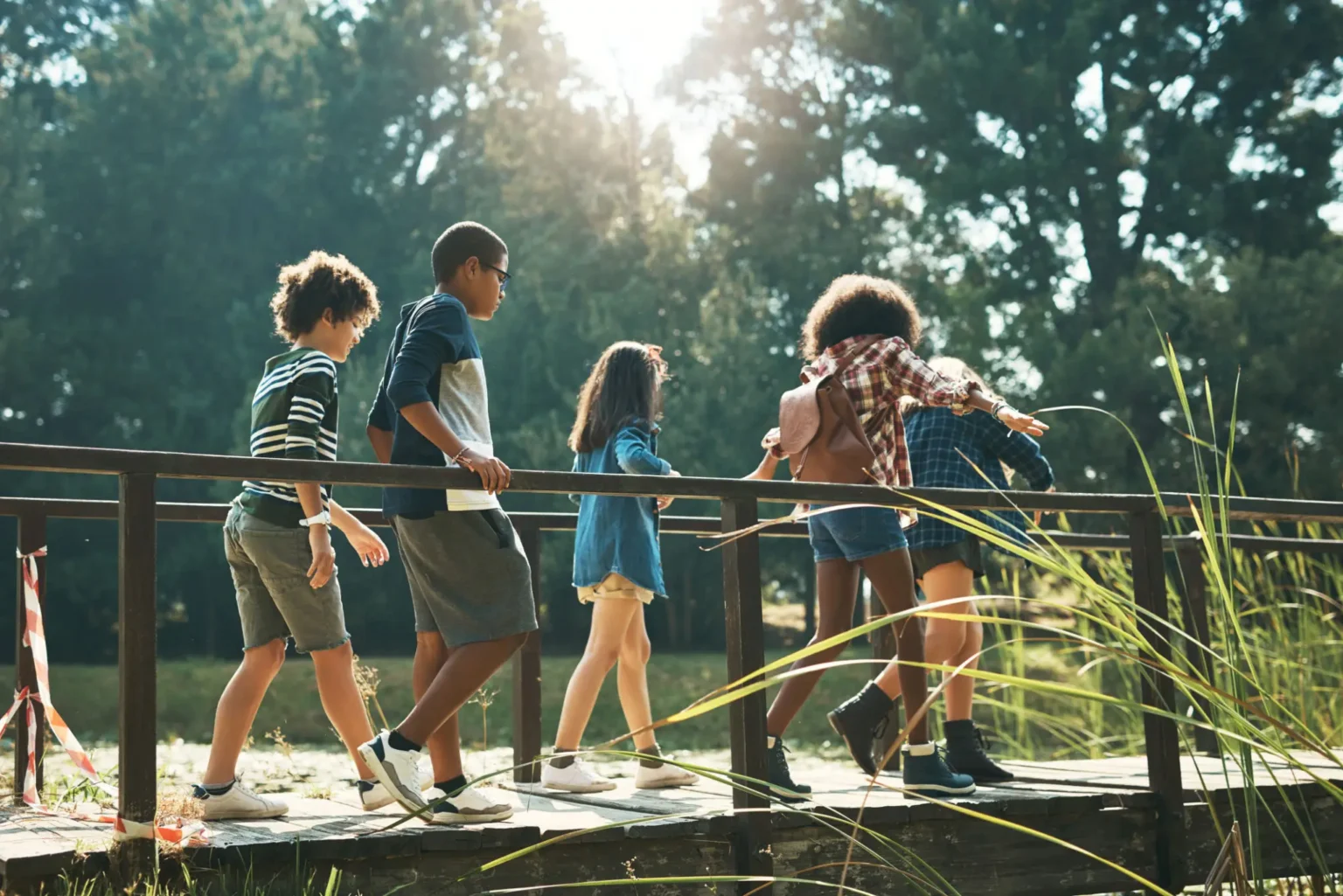 Children walking across wooden bridge in park